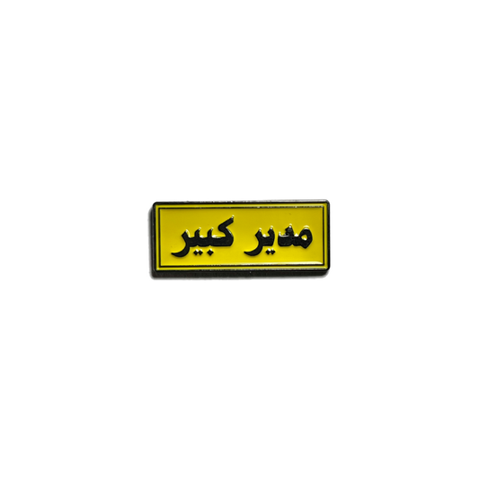 Arabic yellow metal pin with black text saying “مدير كبير”